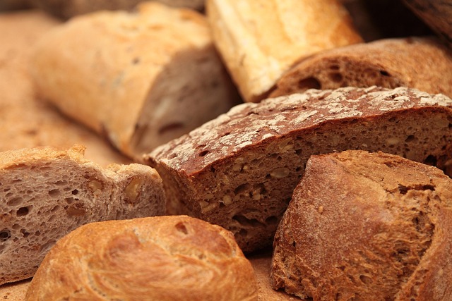 fresh artisan bread loaves on wooden surface with flour dusting and warm bakery lighting