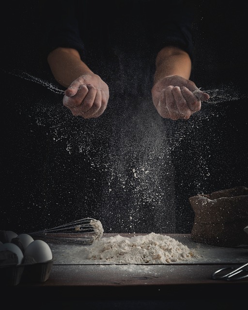 hands kneading bread dough on floured wooden surface with measuring tools and ingredients nearby